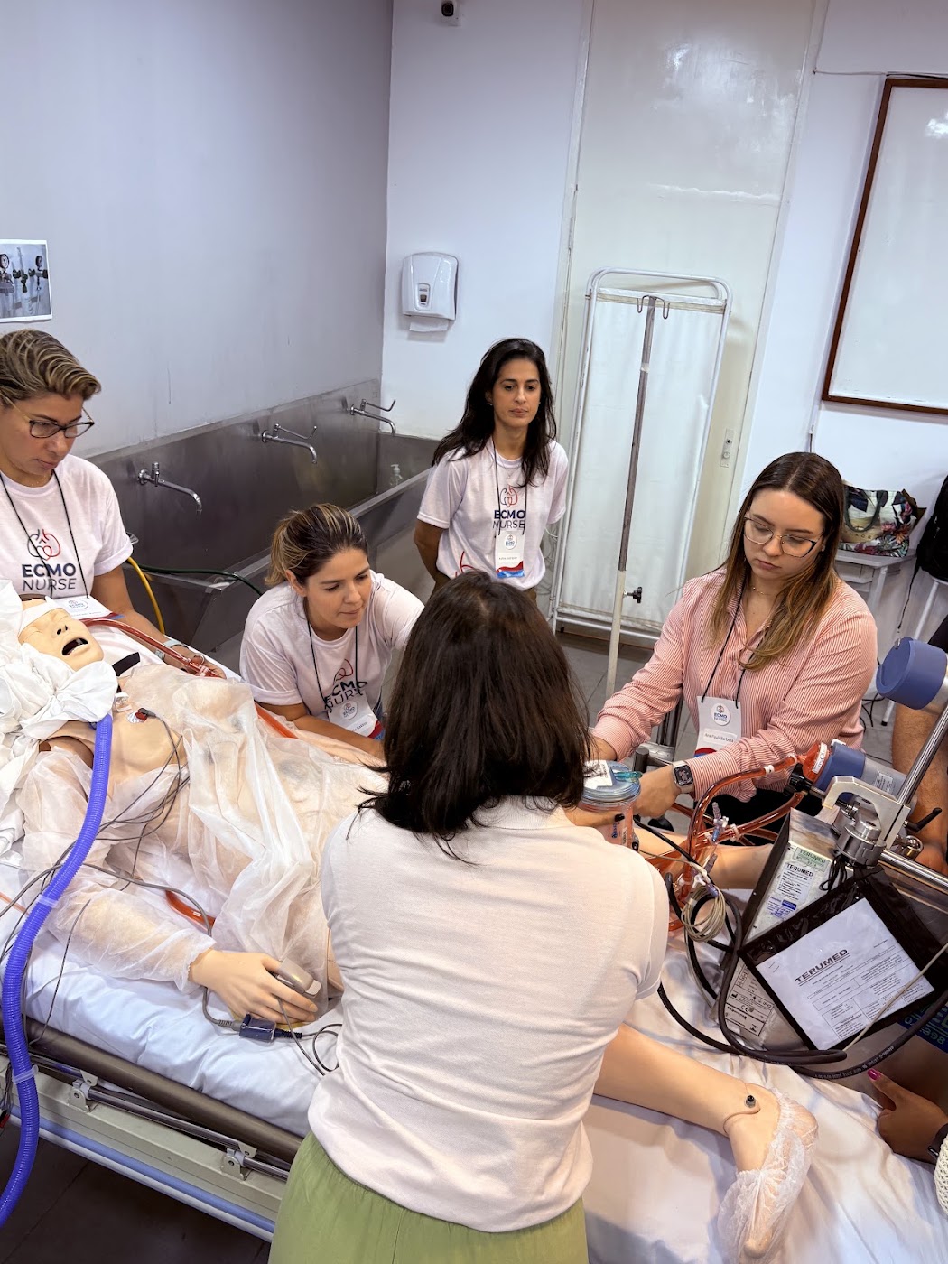 Alunas de camiseta ECMO NURSE durante simulação realística com circuito de ECMO em manequim